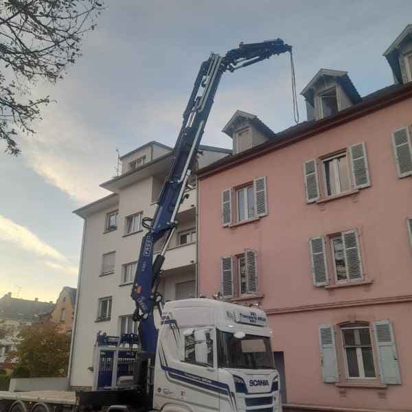 Camion-grue Scania en levage le long d’un immeuble, en centre-ville