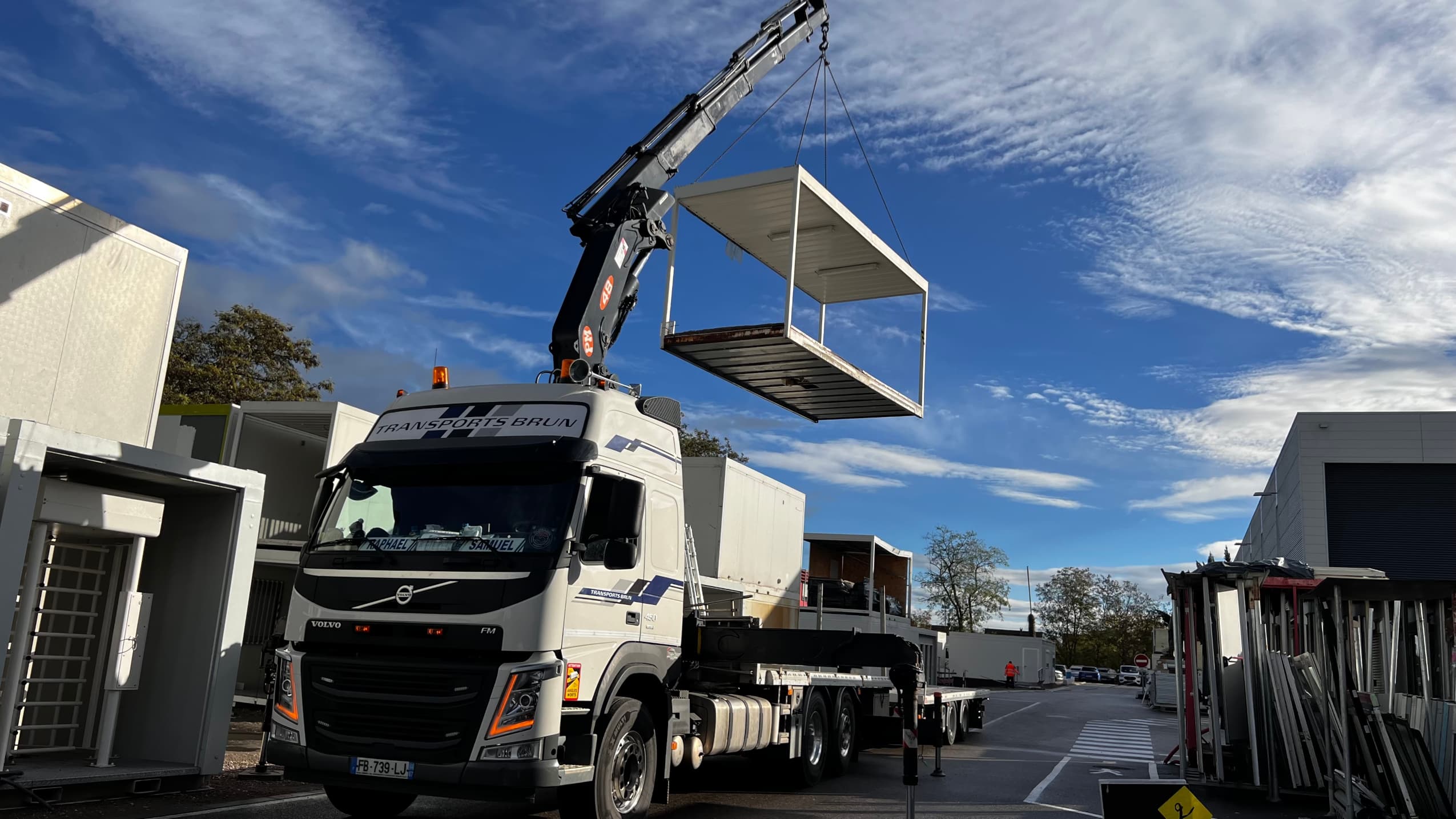 Camion-grue Volvo FM de Transports Brun soulevant un module préfabriqué sur une zone d’activité