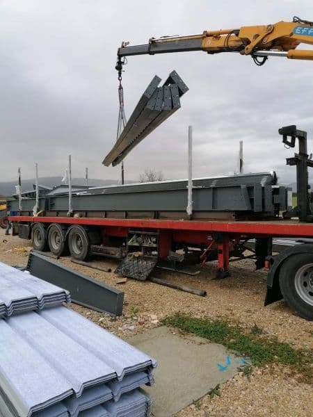Déchargement à la grue de poutrelles en acier depuis un plateau