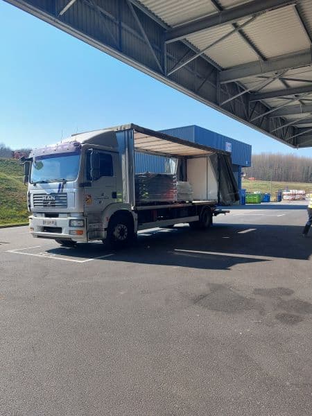 Porteur bâché, rideau latéral ouvert, sous l’auvent d’un quai de chargement