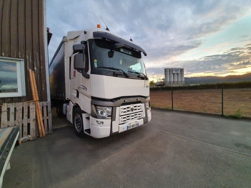Tracteur Renault T attelé à une semi-remorque, le long d’un bâtiment en bois