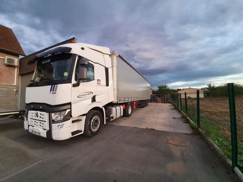 Tracteur Renault T et semi-remorque bâchée le long d’une clôture