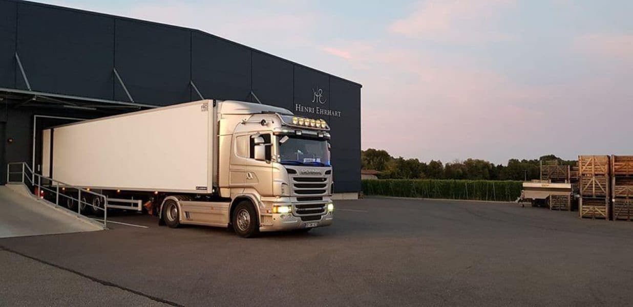 Tracteur Scania et semi-remorque fourgon devant un entrepôt, au crépuscule