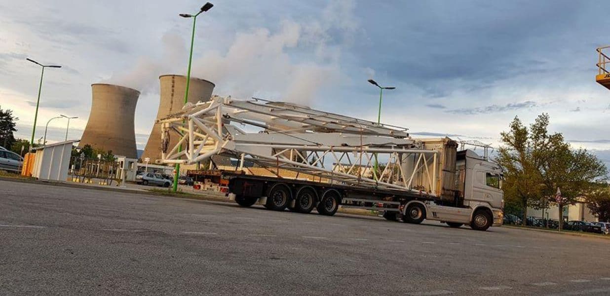 Semi-remorque chargée d’une structure métallique, tours de refroidissement d’une centrale en arrière-plan