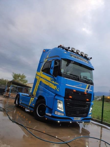 Tracteur Volvo FH bleu et jaune sur un sol mouillé
