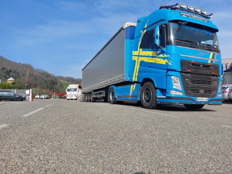 Tracteur Volvo FH bleu et jaune avec une semi-remorque bâchée