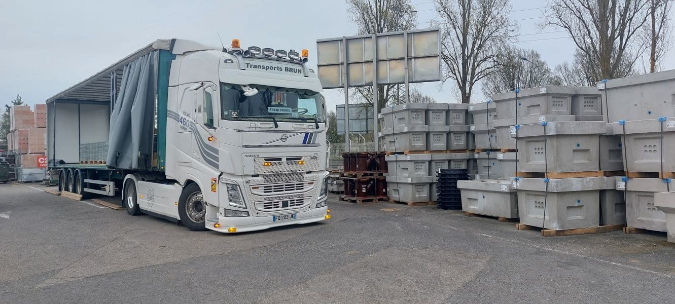 Semi-remorque tautliner ouverte sur le côté, tractée par un Volvo FH, sur une aire de chargement