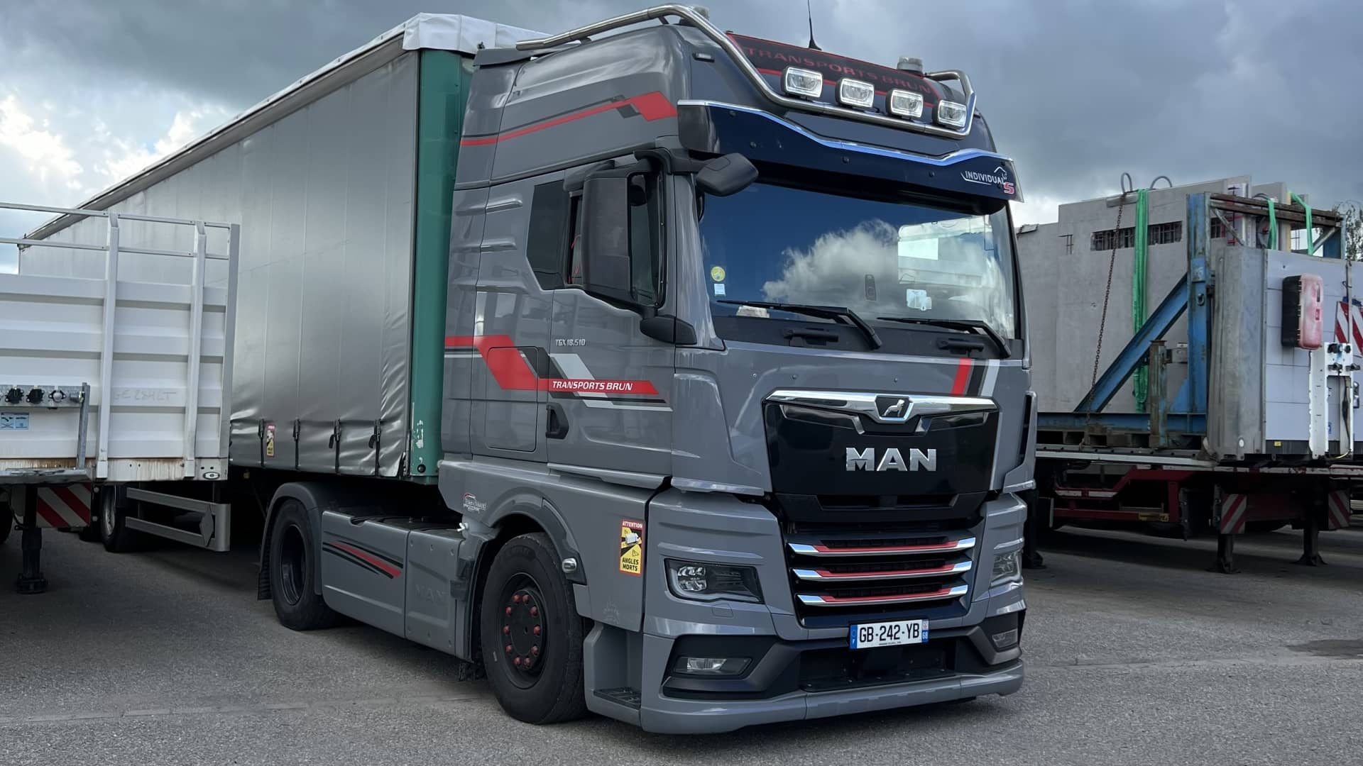 Tracteur MAN TGX gris et semi-remorque bâchée