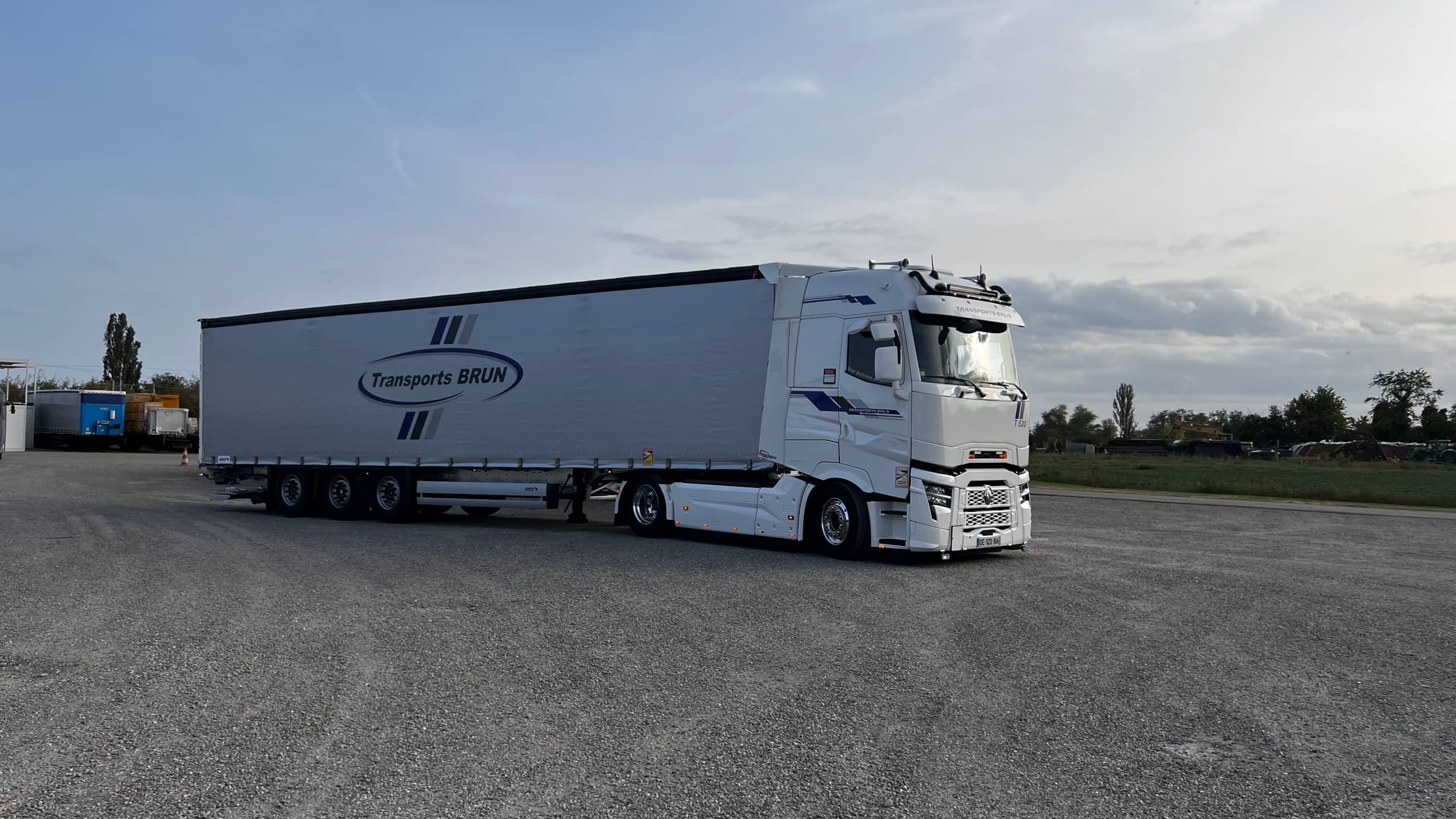 Tracteur Renault T et semi-remorque bâchée Transports Brun sur une aire de stationnement